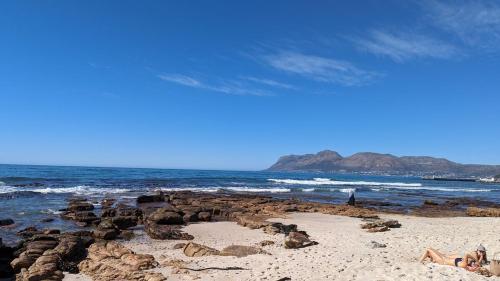 a beach with rocks and the ocean with people on it at Dalebrook Sea-Facing Apartment in Kalk Bay in St James