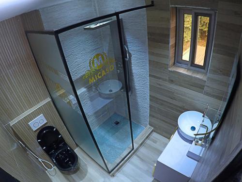 a bathroom with a glass shower and a toilet at MICASO Guest House in Limbe