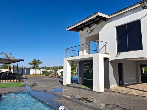 a white house with a balcony and a swimming pool at The Private Location in Thohoyandou