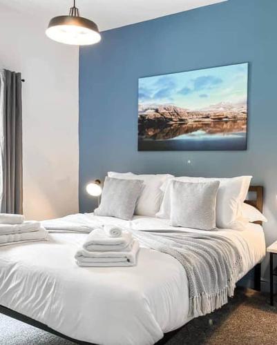 a bedroom with a white bed with a blue wall at Pavilion Mews Luxury Apartment in Buxton