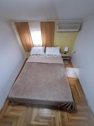 Una cama grande en una habitación pequeña con suelos de madera. en Rooms3, en Beograd