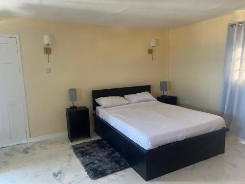 a bedroom with a bed with white sheets and a window at Lovely 2 bedroom in the city in Saint Georgeʼs