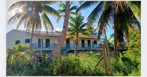 a white house with palm trees in front of it at Villas do paraíso brisa in Marau