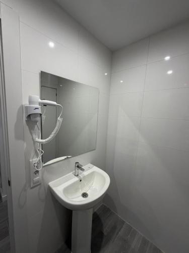 a white bathroom with a sink and a mirror at Hostel Hock Residences in Hospitalet de Llobregat