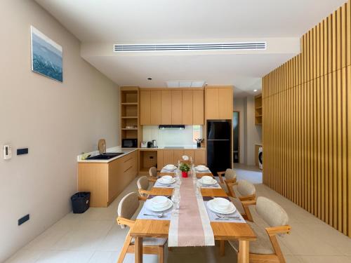 a kitchen with a long wooden table and chairs at Luxury 3-Bedroom Pool Villa Long One B9 with Panoramic Chalong Bay View in Ban Bo Rae