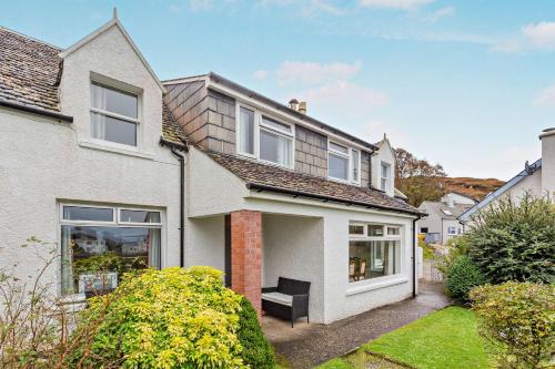 a white house with a bench in the front yard at Hillside in Kyleakin