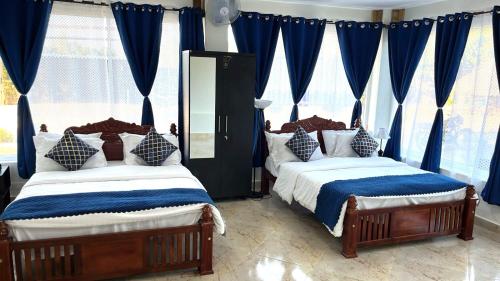 zwei Betten in einem Schlafzimmer mit blauen Vorhängen in der Unterkunft Chan Beach Resort & Hotel in Bahūr