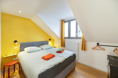 - une chambre avec un lit et un mur jaune dans l'établissement Chez Arlette - Neuf - Haut de Gamme - Tram - Proche centre-ville - Tout confort, à Strasbourg