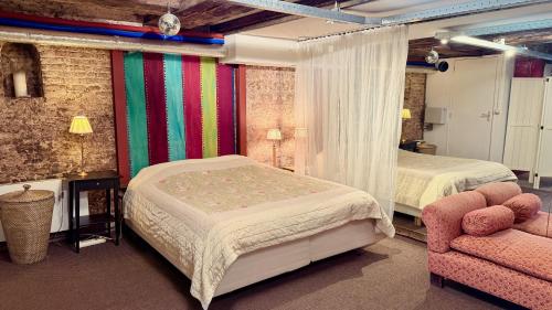 a bedroom with two beds and a chair at Top-notch space along canal in historic centre in Amsterdam
