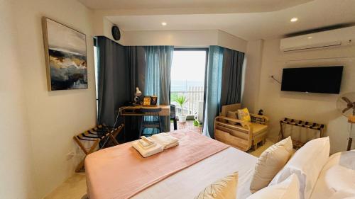 Un dormitorio con una cama y un televisor. en TDJ Japandi Studio in Tambuli Seaside Living Fully Equipped, en Maribago