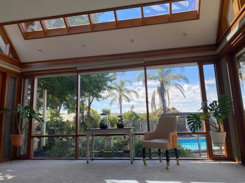 a living room with large windows and a table and chairs at Hillside Retreat with Pool in Flagstaff Hill