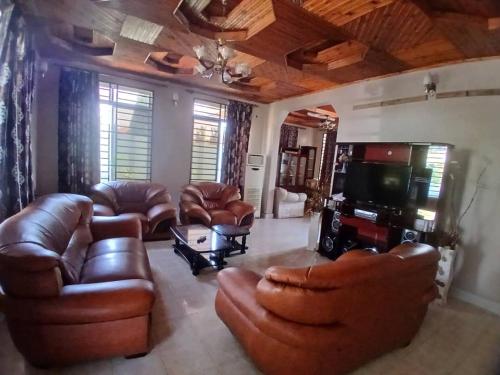 a living room with leather furniture and a flat screen tv at The Secret Garden Hotel Moshi in Moshi