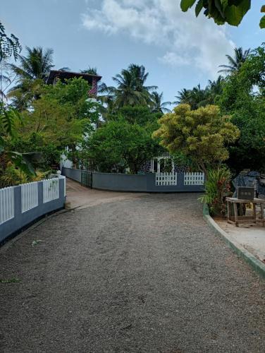 a driveway with a white fence and trees at Villa Onus in Aluthgama
