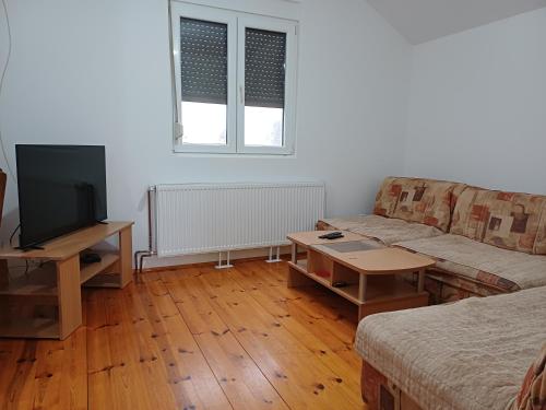 ein Wohnzimmer mit einem Sofa und einem Tisch mit einem TV in der Unterkunft Apartman Branko in Kolašin