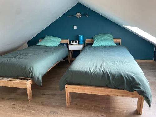 two beds in a room with blue walls at L'étable de Keriven in La Chapelle-Neuve