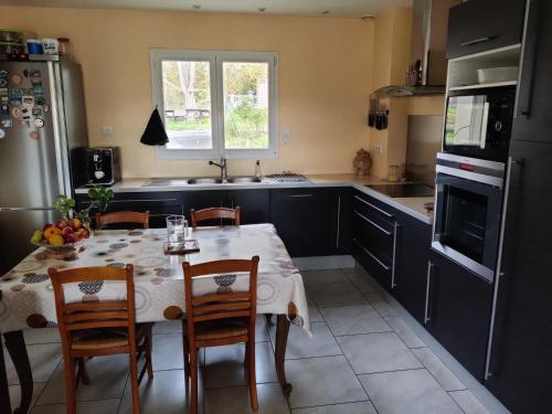 a kitchen with a table with chairs and a refrigerator at chambre dans une maison 