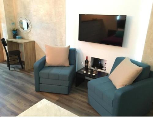 a living room with two blue chairs and a flat screen tv at Apartman broj 19 in Banja Koviljača