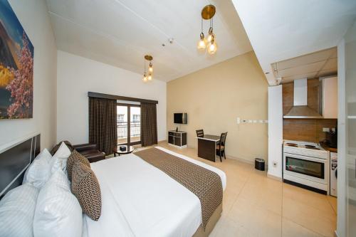 a bedroom with a white bed and a kitchen at City Stay Residences - Serviced Apartments DIP in Dubai