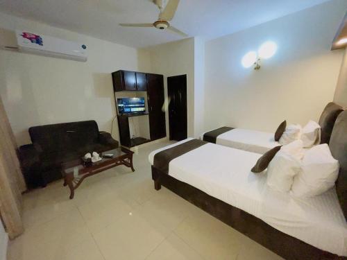 a hotel room with two beds and a couch at Royal Ilva Hotel in Lahore