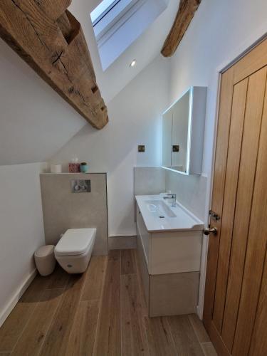 a bathroom with a sink and a toilet and a skylight at Malthouse Barn, Staffordshire in Gnosall