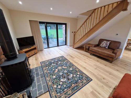 a living room with a wood stove and a couch at Malthouse Barn, Staffordshire in Gnosall