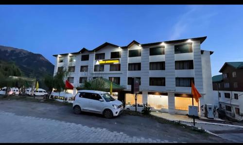 a white car parked in front of a building at Hotel Natraj International in Patnitop