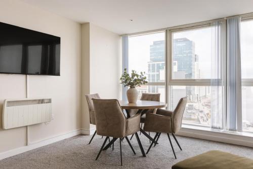 a dining room with a table and chairs and a large window at Exclusive 2BR Apartments By Luxus in Belfast