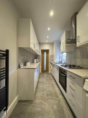 a large kitchen with white cabinets and appliances at Serenity LTD in Leicester