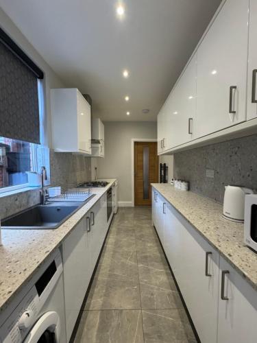 a kitchen with white cabinets and a sink at Serenity LTD in Leicester