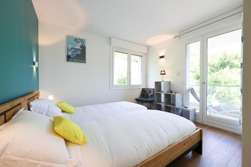 una camera bianca con un grande letto con cuscini gialli di L'Hermitage lake view a Talloires