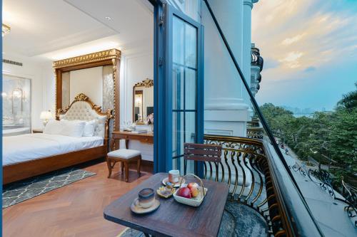 a room with a balcony with a bed and a table at Victoria Suites Westlake Hanoi in Hanoi