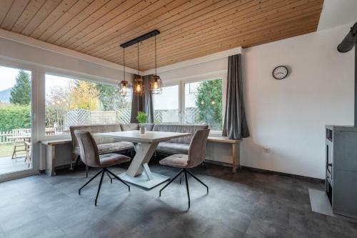 a dining room with a table and chairs and windows at Ferienhaus Gehrenblick in Oberletzen