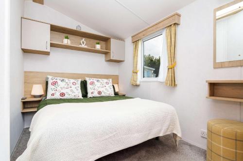 a small bedroom with a bed and a window at 3Bed Caravan - Muirfield in Port Seton