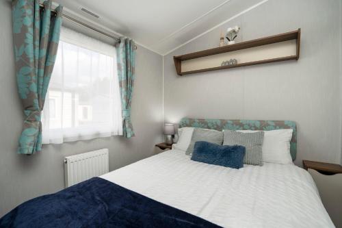 a bedroom with a bed with a blue and white blanket at Seton Sands-3 Bed Static Caravan in Port Seton