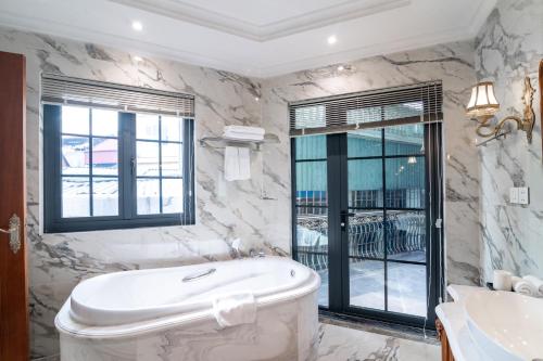 a white bathroom with a tub and a window at Victoria Suites Westlake Hanoi in Hanoi