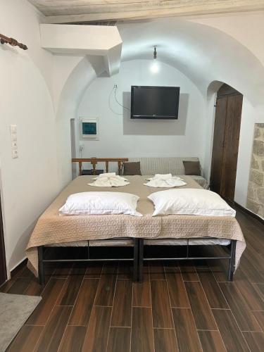 a bedroom with a large bed with a tv on the wall at Eleonoras House in Leonidio