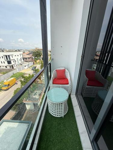 uma varanda com uma cadeira, uma mesa e uma vista em Palm & Pearl Apartment em Lekki