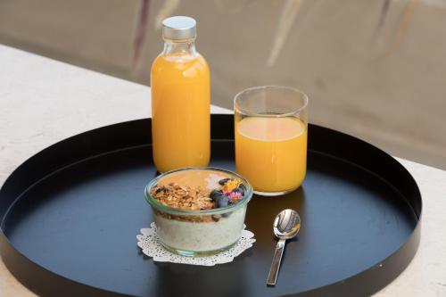 Epos Villas Imerovigli في إيميروفيغلي: طبق أسود عليه وعاء من حبوب الإفطار وكوب من عصير البرتقال