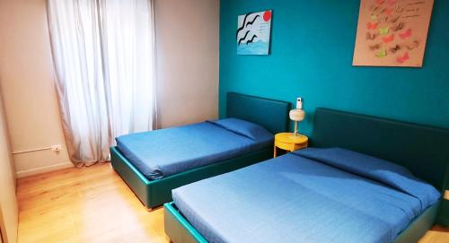 twee bedden in een slaapkamer met blauwe muren bij Casa Santarelli in Rome