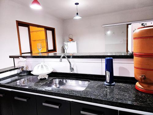 a kitchen counter with a sink and a mirror at Temporada Belas Casas in São Pedro
