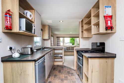 een keuken met houten kasten en een kookplaat met oven bij 3 Bedroom Caravan - Seton Sands in Port Seton