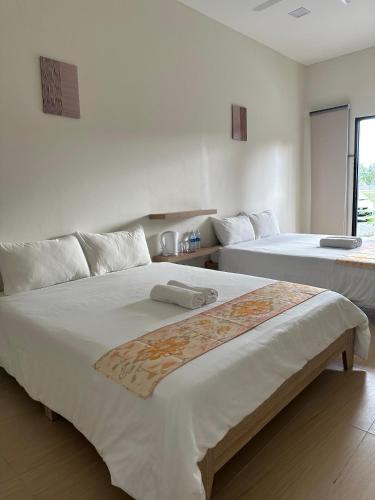two beds in a white room with a window at Cerya Kampung Inn in Cherating