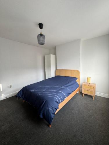 レスターにあるSerenity LTDの青い毛布が掛けられたベッドのある寝室