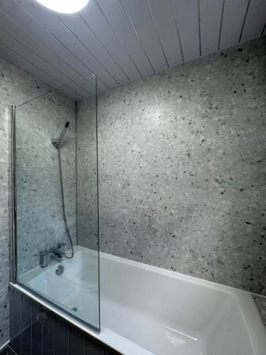 レスターにあるSerenity LTDの浴槽とガラスのシャワー付きのバスルーム