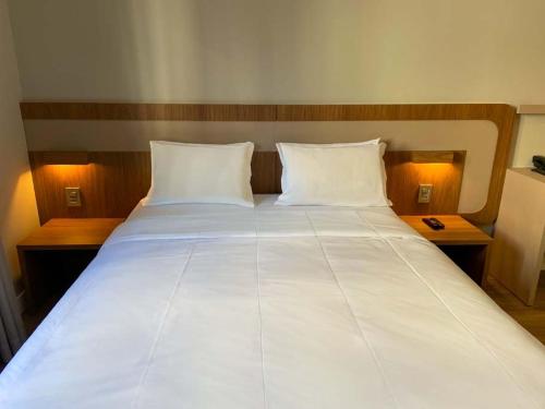 a large white bed with two pillows on it at Slaviero Curitiba Shopping in Curitiba