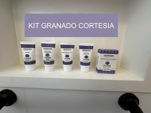 une étagère avec quatre bouteilles de Kitt Grandapocticaaments dans l'établissement Studio de Alto Padrão no Jardim Aquarius, à São José dos Campos