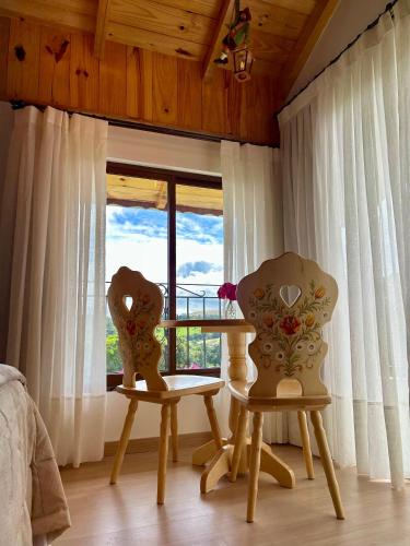 due sedie e un tavolo in una stanza con una finestra di Pousada Pattis a Treze Tílias