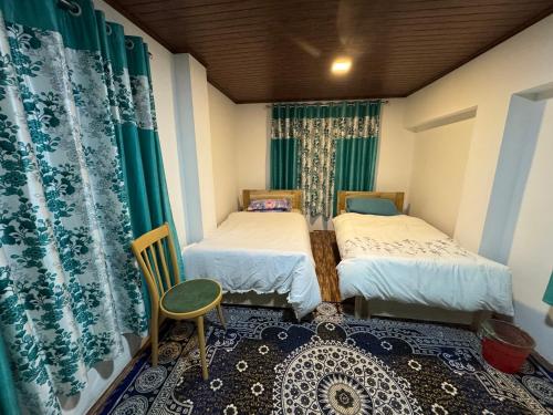 Una pequeña habitación con dos camas y una silla. en Sungava homestay, en Mirik