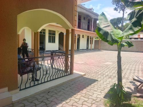 a palm tree next to a building with a fence at Guardian Motel Kasese in Kasese