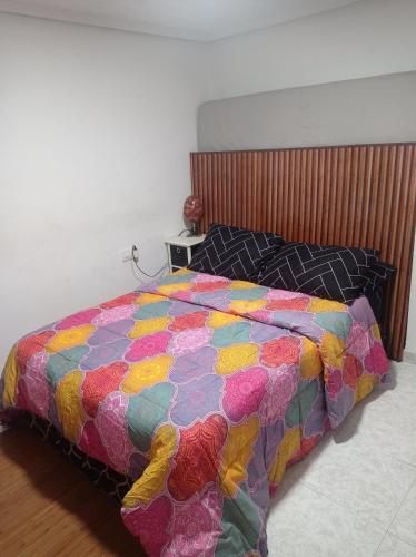 a bed with a colorful comforter in a bedroom at Habitación en piso Compartido 1-Familiar-Valencia Centro in Valencia